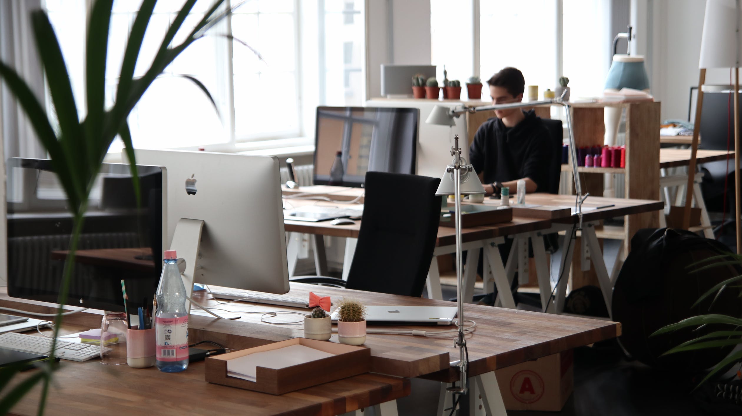 Office space with desks and computers. A man sits at a computer.