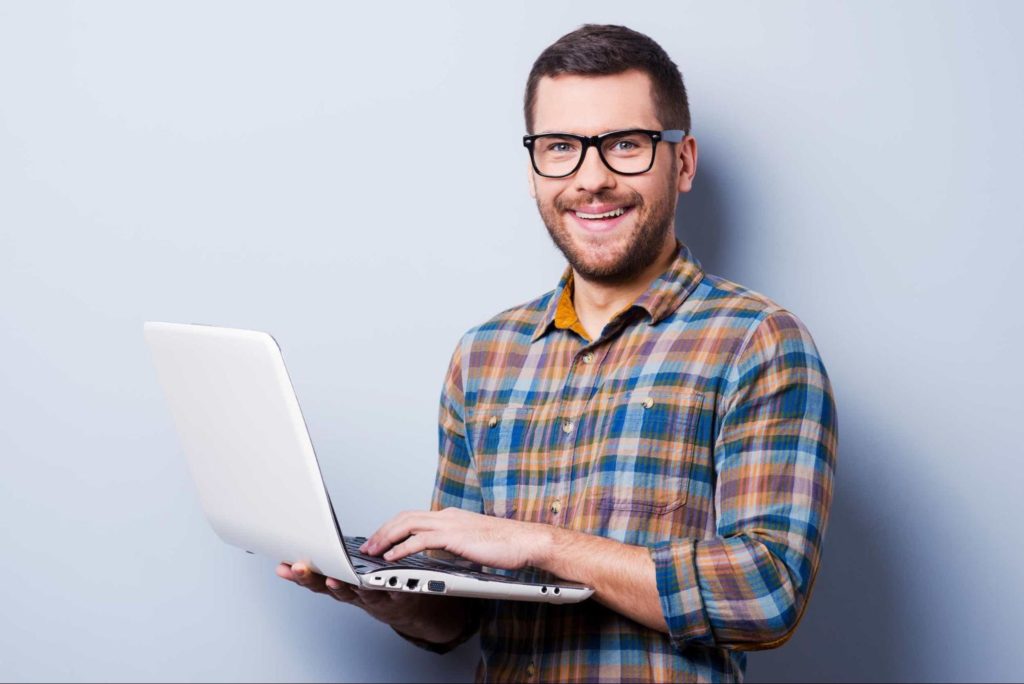 Man smiling and holding a white laptop