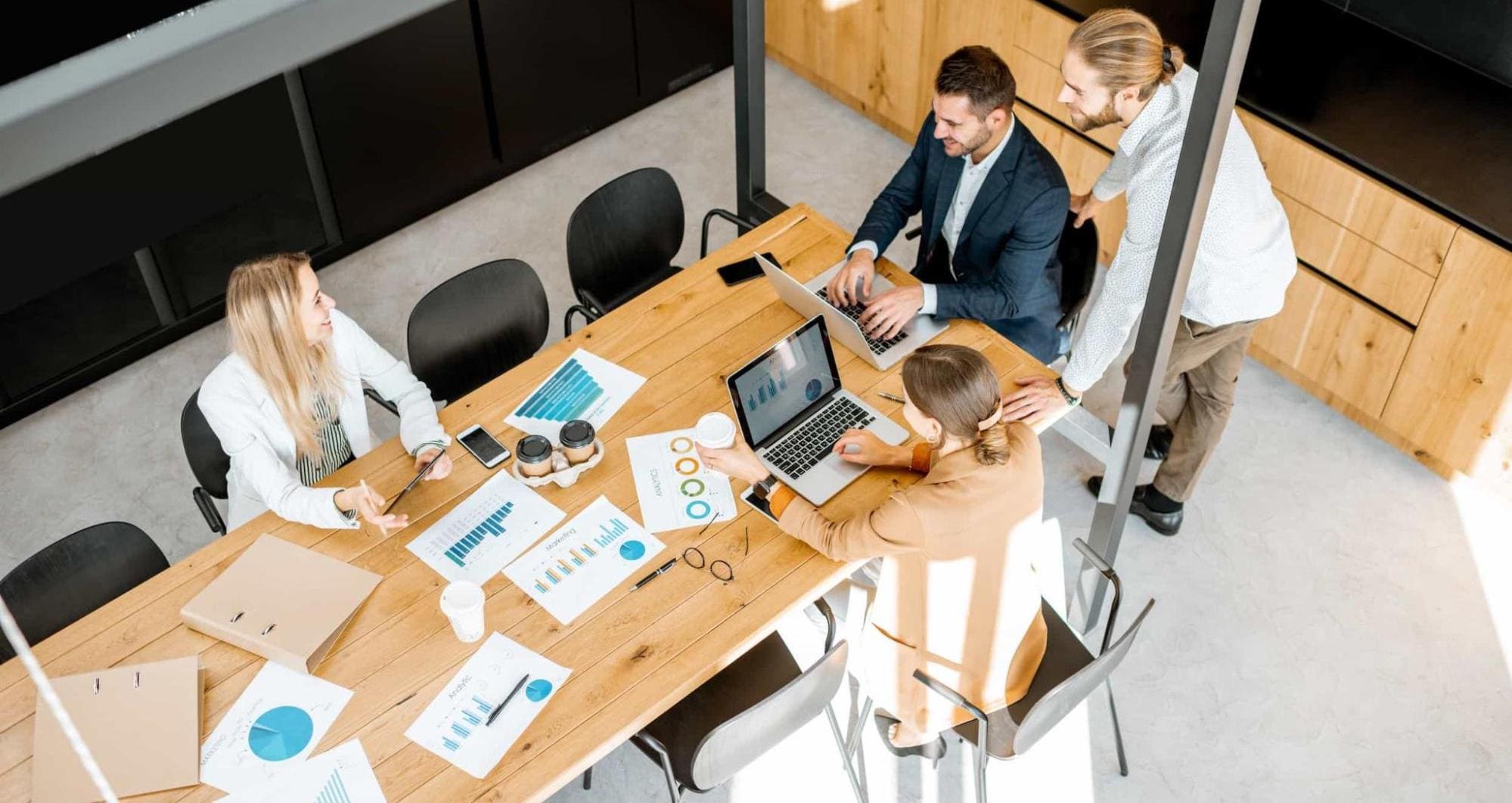 A group of people sitting in an office working on their laptops while talking